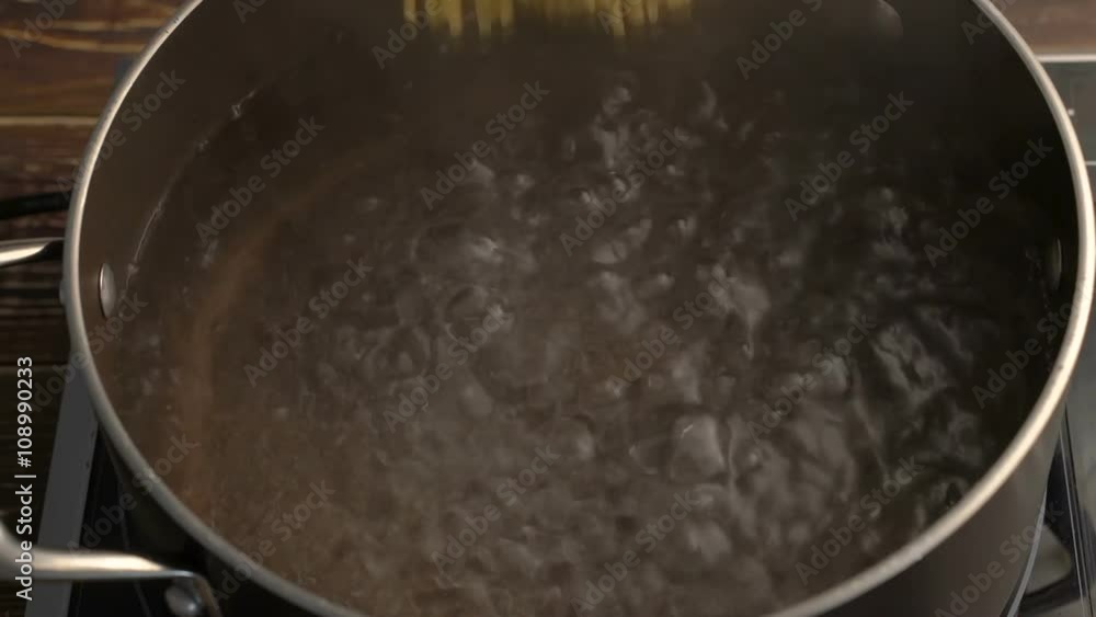 Man's hand put spaghetti pasta into boiling water Man's hand put spaghetti pasta into boiling water