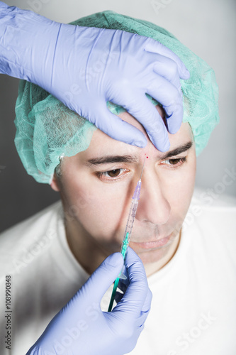 Doctor aesthetician makes face beauty injections to male patient