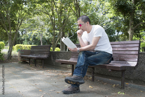 公園のベンチで本を読む男性