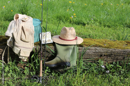 Un équipement complet de pêche à la mouche posé sur une poutre en bois dans un pré photo