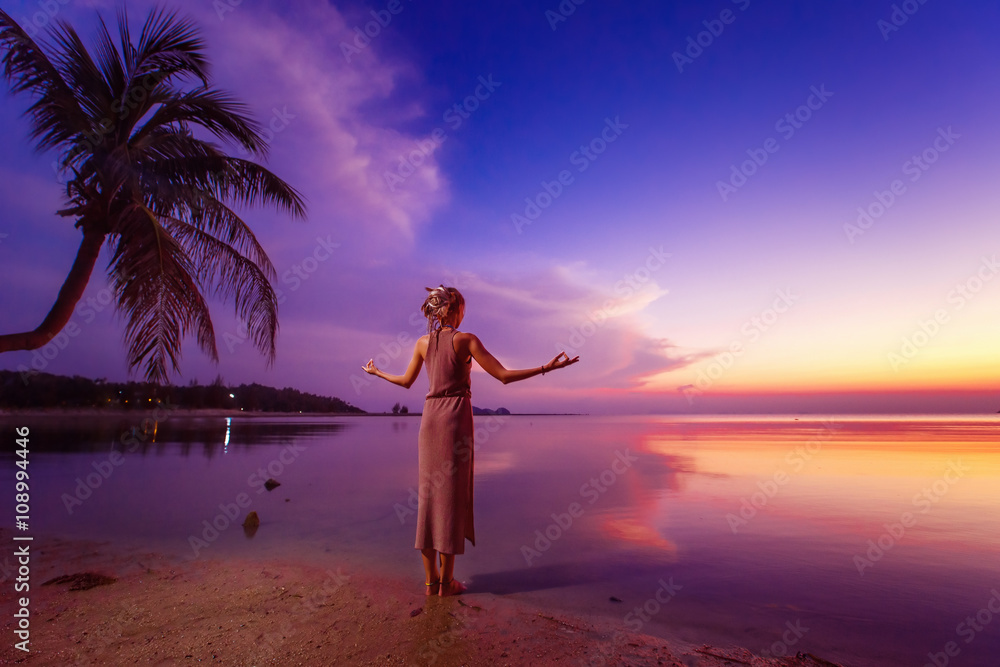 Fototapeta premium Young woman is standing relaxed at deep blue tropical sunset