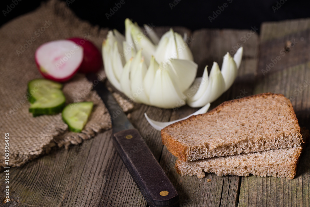 Rye bread, vegetables and knife on an old table Rye bread, vegetables and knife on an old table