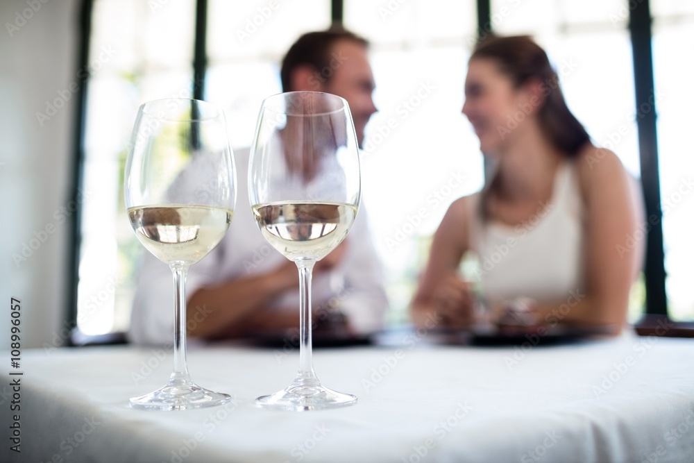 Close up of two wine glasses and couple in background Close up of two wine glasses and couple in background