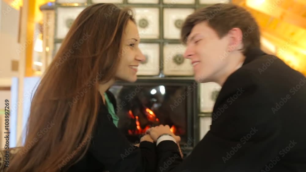 A couple holding hands and kissing near the fireplace. A couple holding hands and kissing near the fireplace.