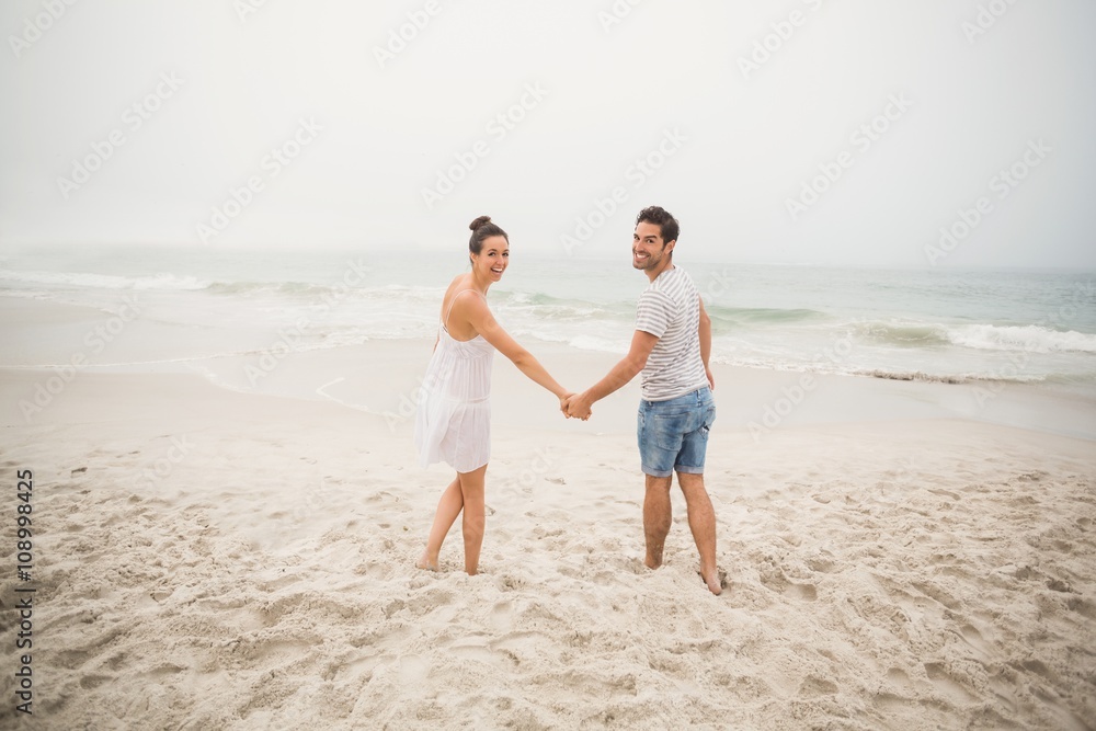 Portrait of couple holding hands and walking on the beach