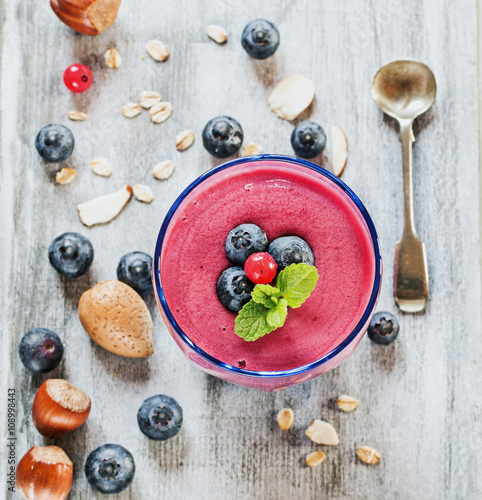 Smoothie with berries, nuts, almond,oatmeal on wooden tray. Top view. Selective focus.