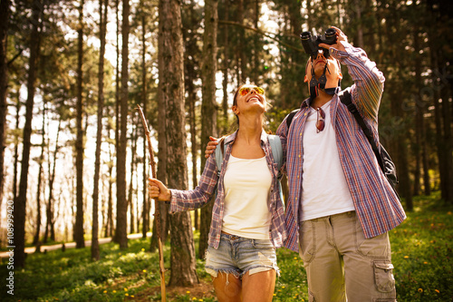 Young couple hiking trough forest and watching birds.Ornithology . photo
