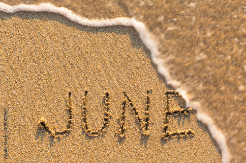 June - word drawn on the sand beach with the soft wave. Months series of 12 pictures.
