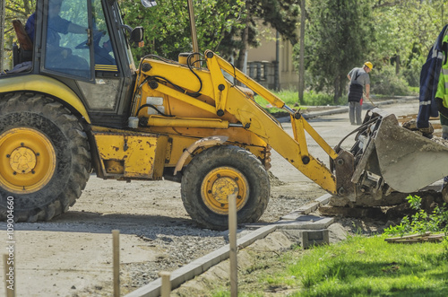 Bulldozer and  worker  preparing the road for asphalting