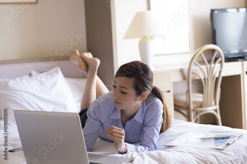Woman is using a laptop lying face down in bed © Monet