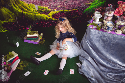 Little girl as Alice in Wonderland pouring tea photo