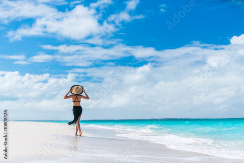 Luxury summer travel beach woman walking by ocean photo