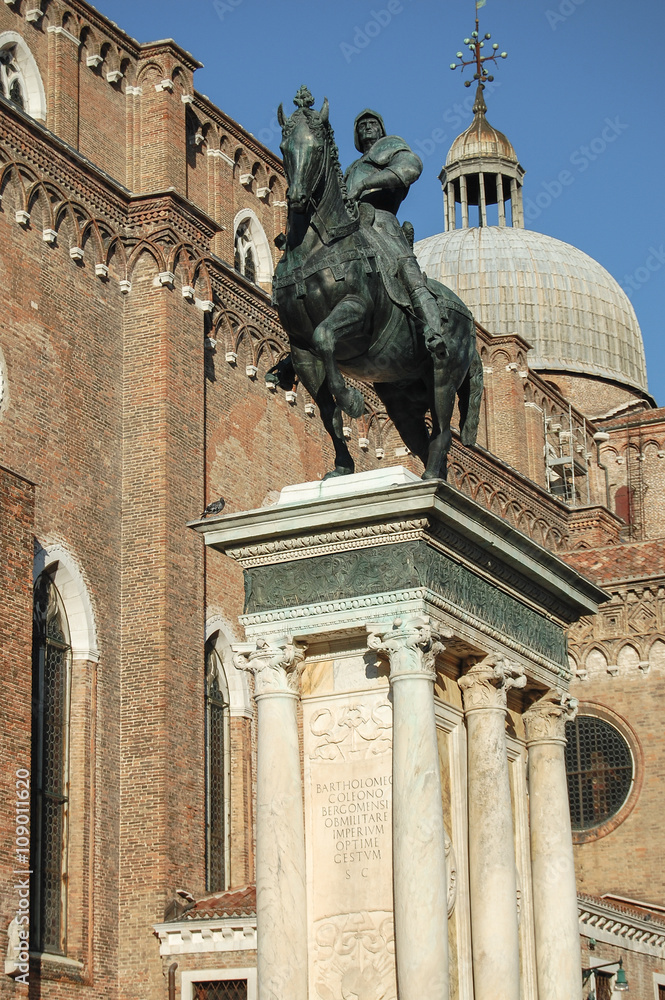 equestrian statue on a high pedestal on a background of the old cathedral
