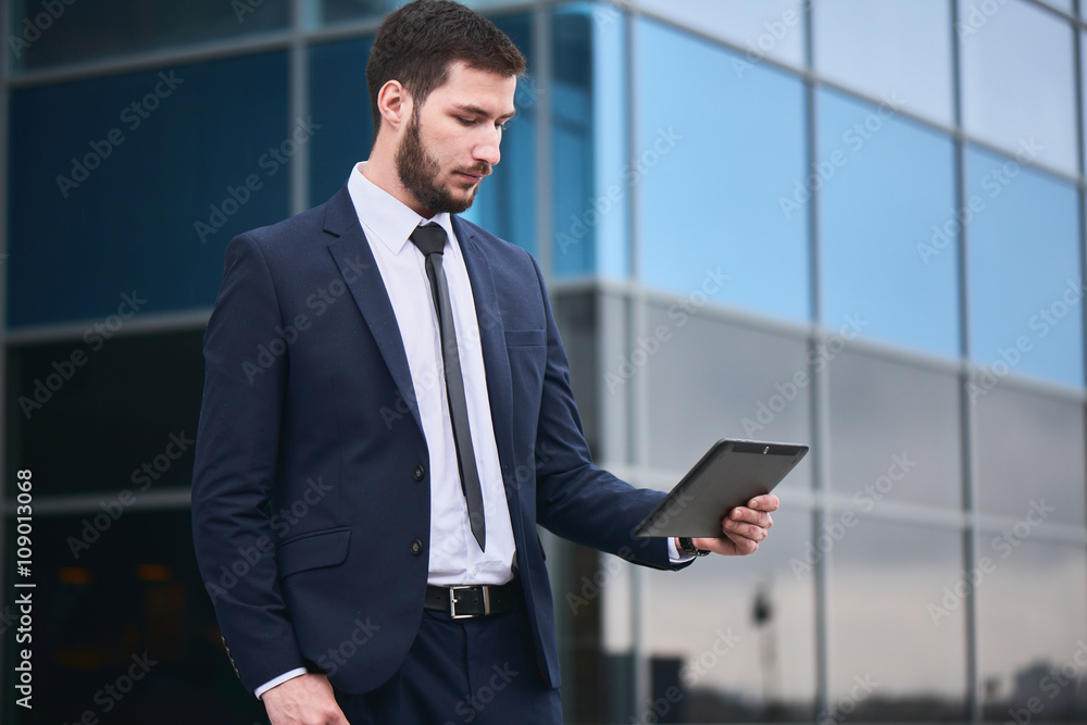 Businessman holding tablet on background of buildings with glass facades Businessman holding tablet on background of buildings with glass facades