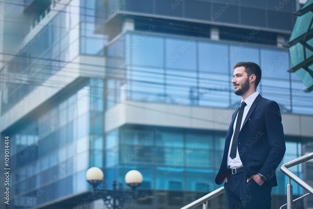 Businessman standing on background of buildings with glass facades