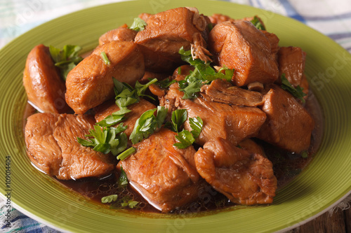 Adobo Chicken with herbs close-up on a plate. horizontal
