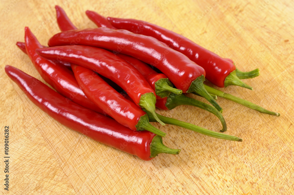 Group of several pile heap red chili or chilli peppers on a wood cutting chopping board photo