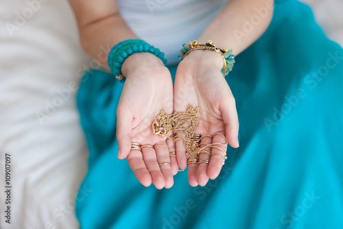 Gold chain in the hands of a young attractive oriental woman. Blurring background. Blue skirt, gold jewelry, Morocco, a bright sunny day.