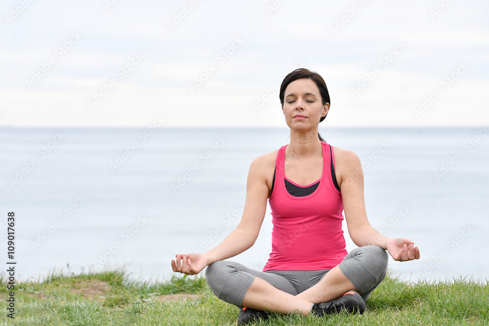 Fitness woman doing relaxation exercises by the sea Fitness woman doing relaxation exercises by the sea