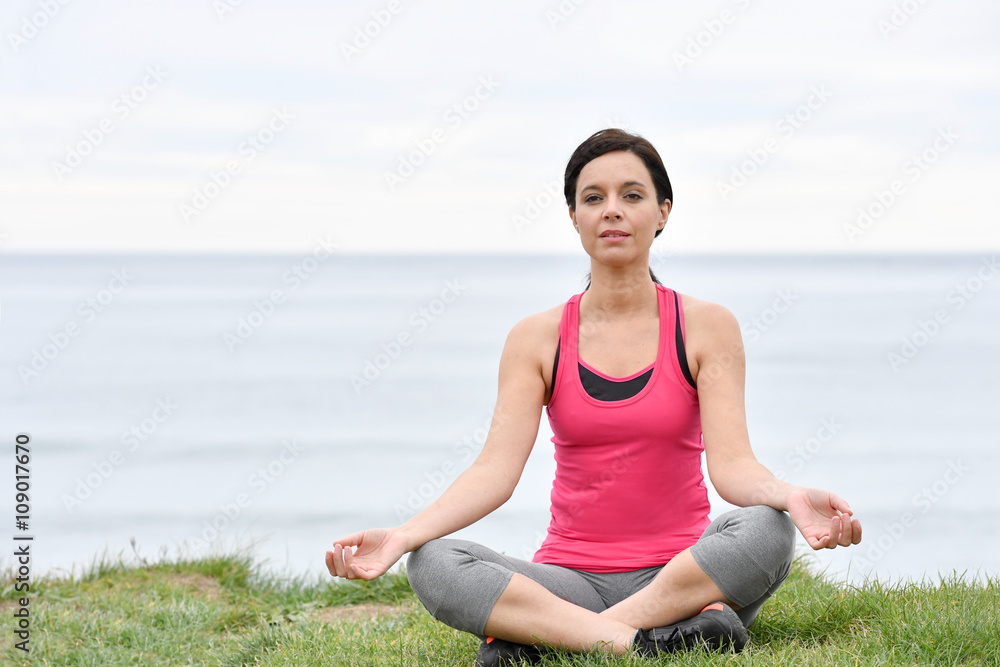 Fitness woman doing relaxation exercises by the sea