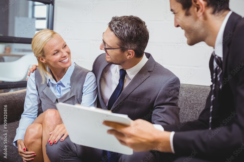 Smiling businesman with clients sitting on sofa Smiling businesman with clients sitting on sofa