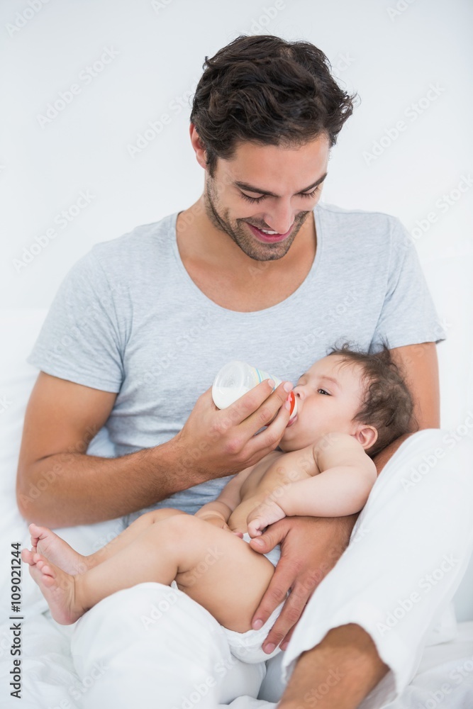 Father feeding milk to daughter at home Father feeding milk to daughter at home