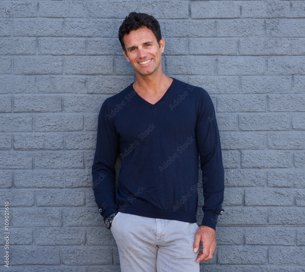 Handsome confident man smiling against gray wall Handsome confident man smiling against gray wall