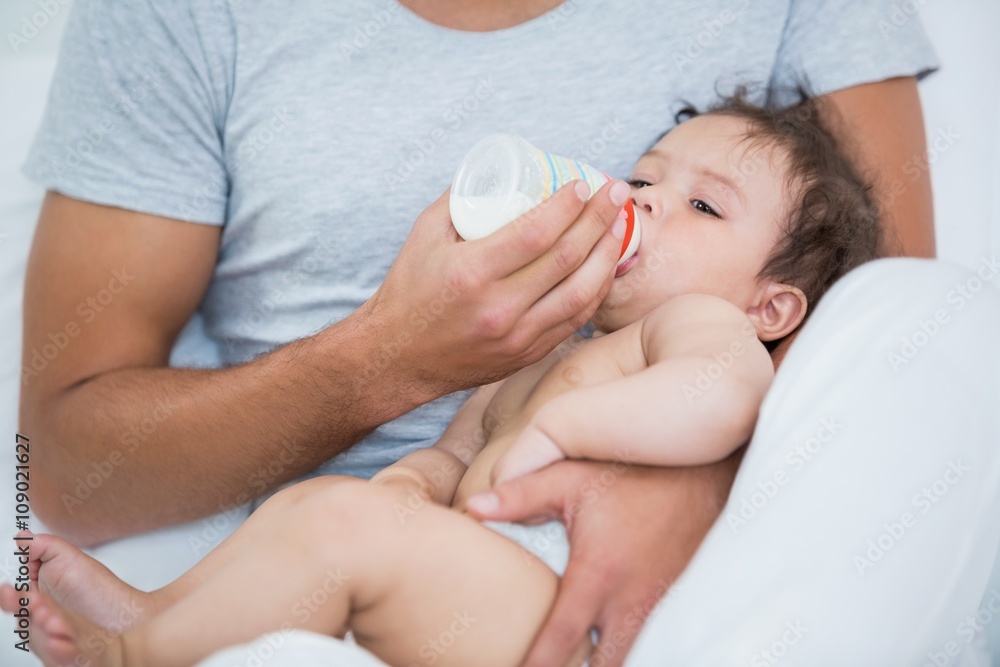 Man feeding milk to baby girl at home Man feeding milk to baby girl at home