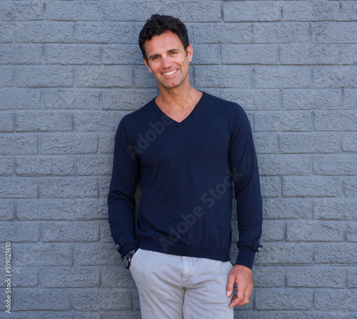 Handsome confident man smiling against gray wall