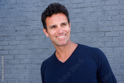 Smiling older man standing against gray wall