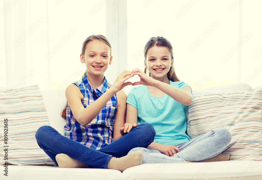 happy little girls showing heart shape hand sign