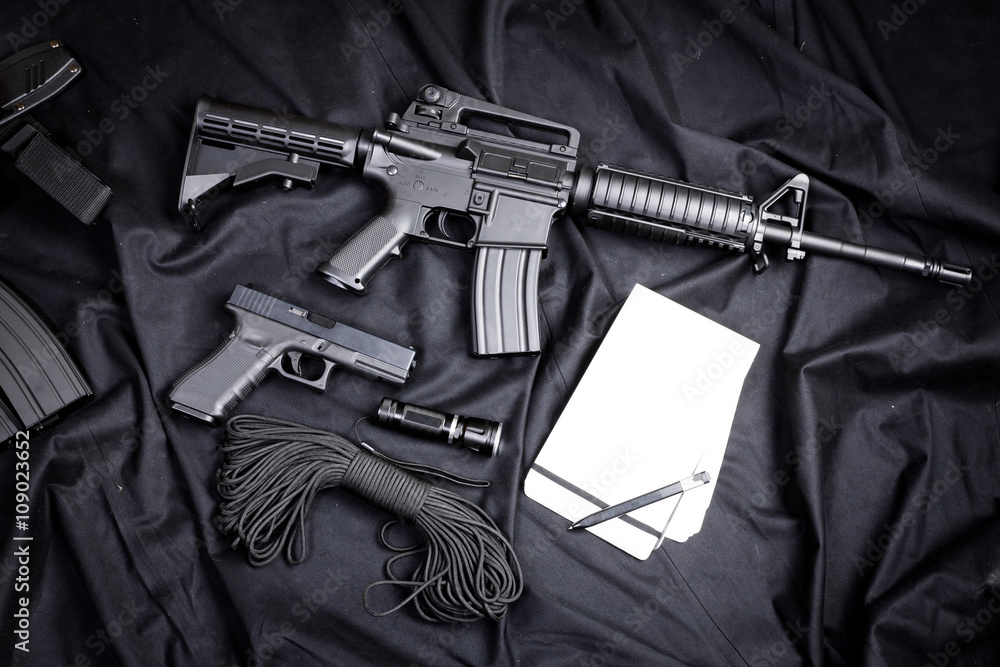Rifle, gun, knife with sheath, compass and notebook with pen on on black cloth Rifle, gun, knife with sheath, compass and notebook with pen on on black cloth