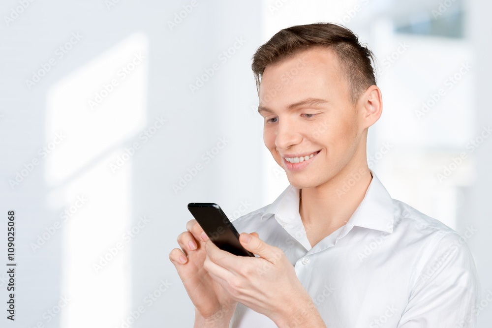 Young man typing text message on his cellphone Young man typing text message on his cellphone