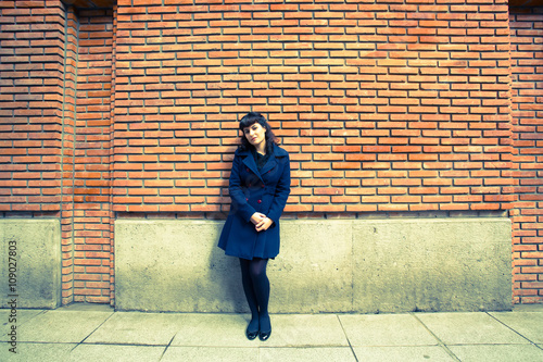 A retro girl waiting in front of a brick wall