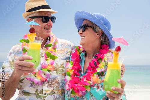Happy senior couple wearing a garland and holding cocktail glass