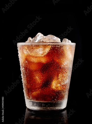 Cold cola with ice in a glass on a black background
