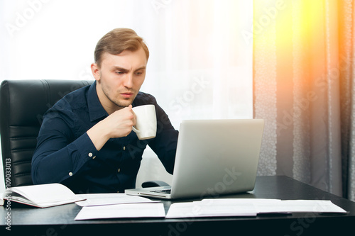 Casual dressed man ready to drink coffee while checking news