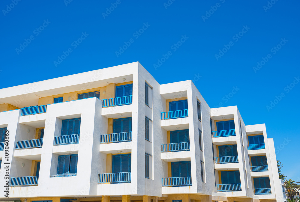 White living house with appartments and balconies in   blue color with sky background