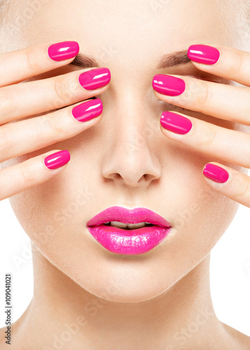 Close-up face of a beautiful girl with pink nails and lips.