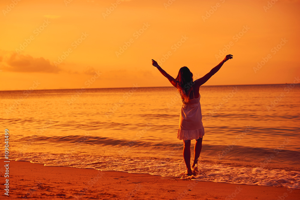Young woman in summer dress enjoying freedom, standing on a ocea