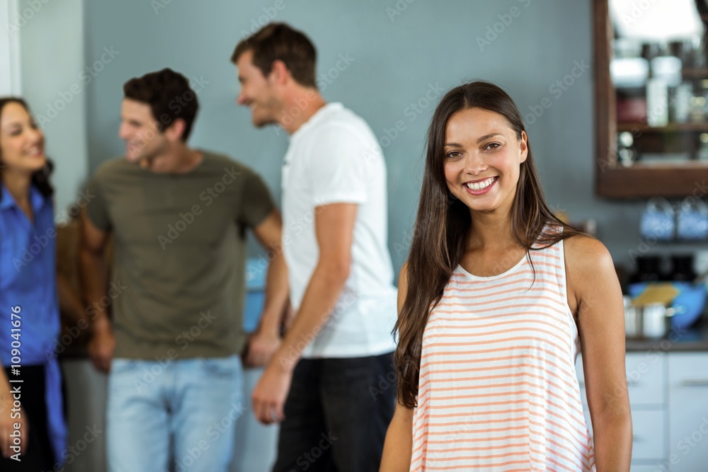 Happy young woman with friends in background at home Happy young woman with friends in background at home