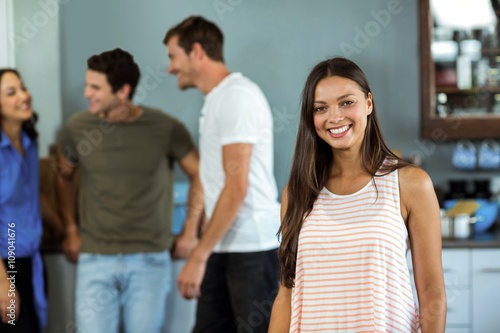 Happy young woman with friends in background at home