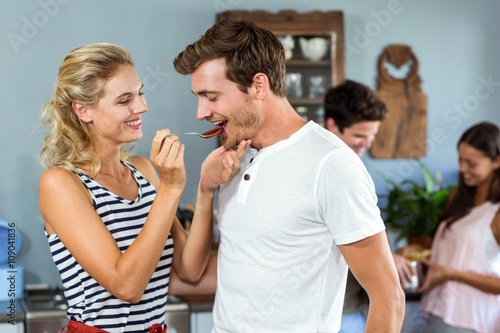 Young woman feeding man at home