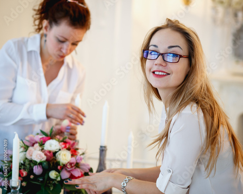 Two young women create a decoration. Decor and floral composition on a table.