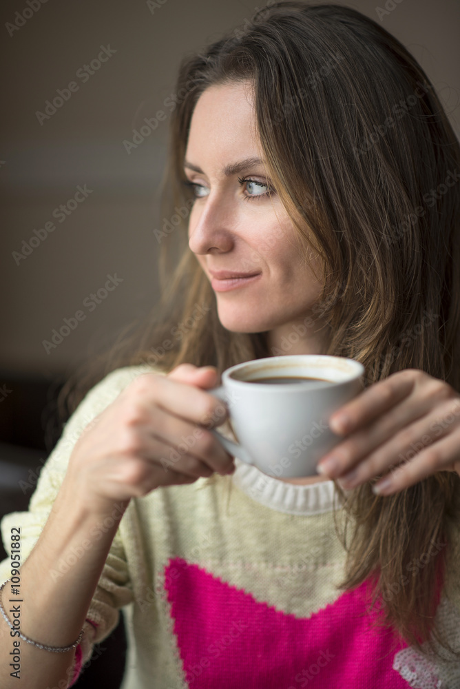 Young girl, sitting in a cafe with cup of coffee.