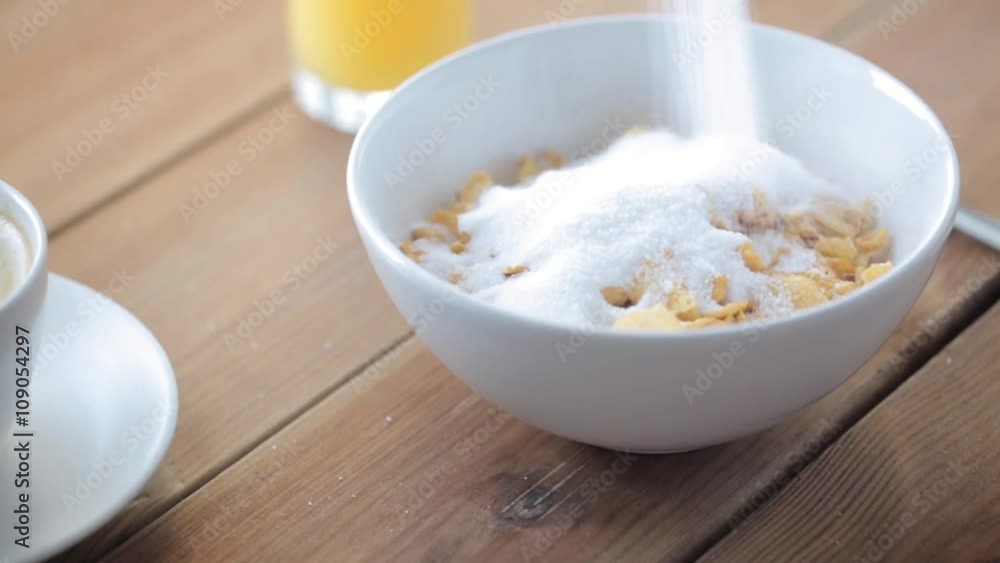 sugar pouring to corn flakes on wooden table sugar pouring to corn flakes on wooden table