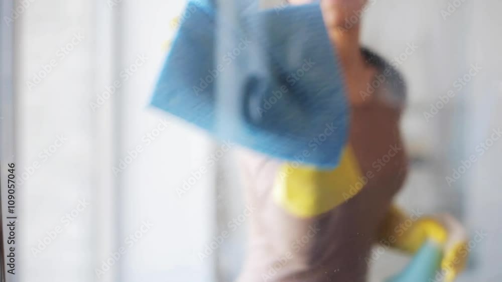 woman in gloves cleaning window with rag and spray woman in gloves cleaning window with rag and spray