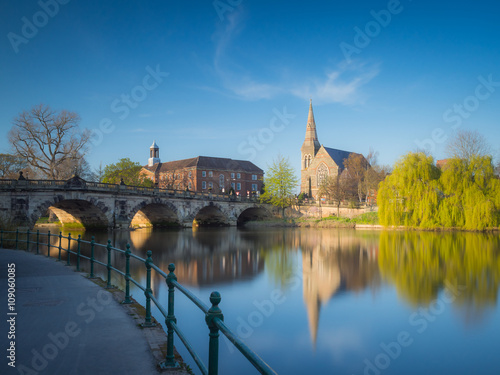 View along the river Severn to the English Bridge, Shrewsbury and a church and prominent willow tree, England, UK. photo