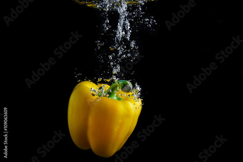 Fresh paprika splash in water with air bubbles. Yellow paprika in water on black background. Healthy food. Wash vegetables.