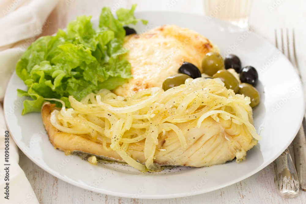 cod fish with onion, mashed potato and salad on white plate and glass of wine